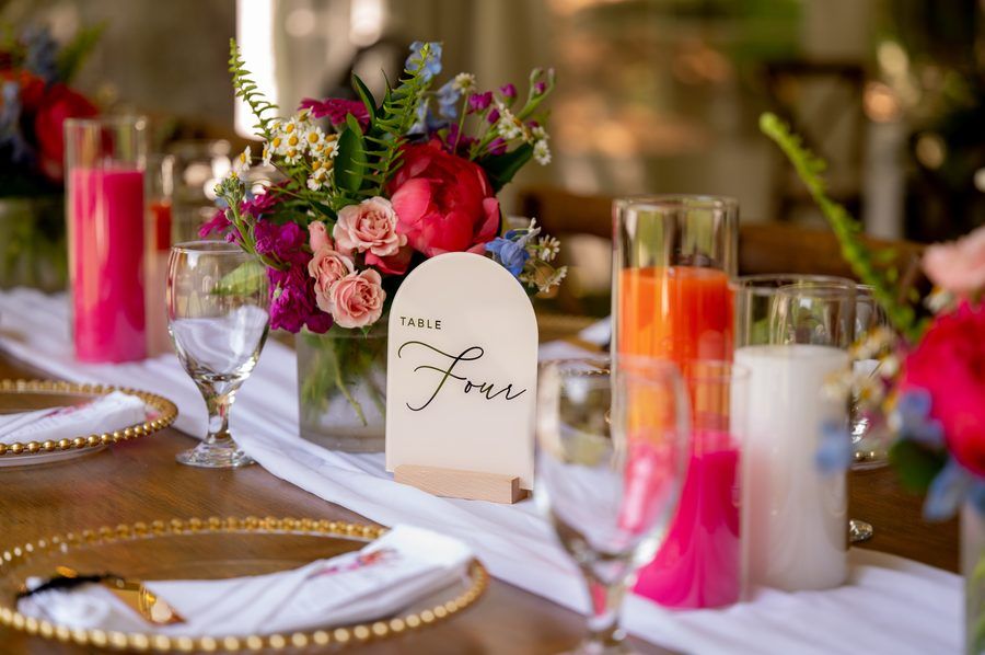 A reception table setting with a table number sign and floral centerpiece